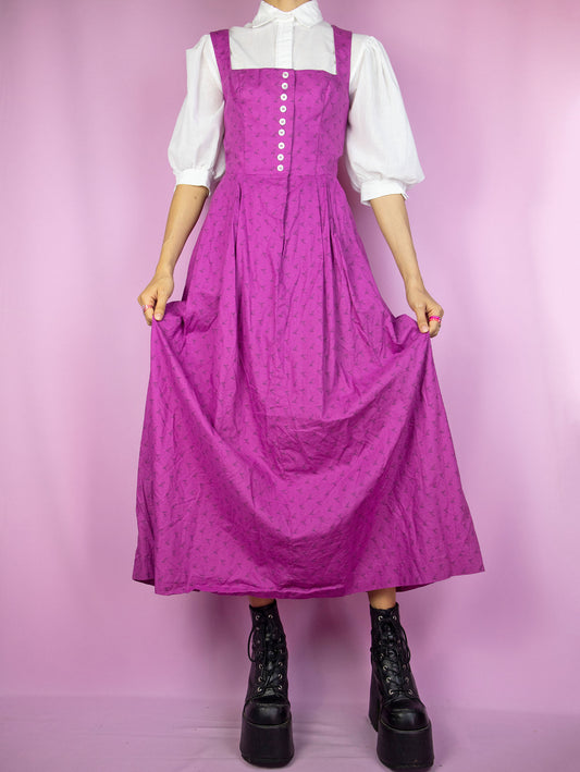 The Vintage 90s Purple Prairie Maxi Dress is a sleeveless floral magenta-pink midi dress featuring delicate pleats and a button-down front. Perfect for a romantic day in the countryside. Please note, the white blouse worn underneath is not included.