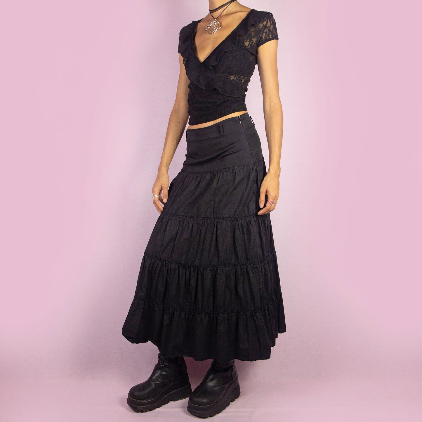 The Y2K Black Tiered Midi Skirt is a vintage 2000s piece featuring a side zipper closure and multiple gathered tiers, creating a flowy and voluminous silhouette. Perfect for summer nights.