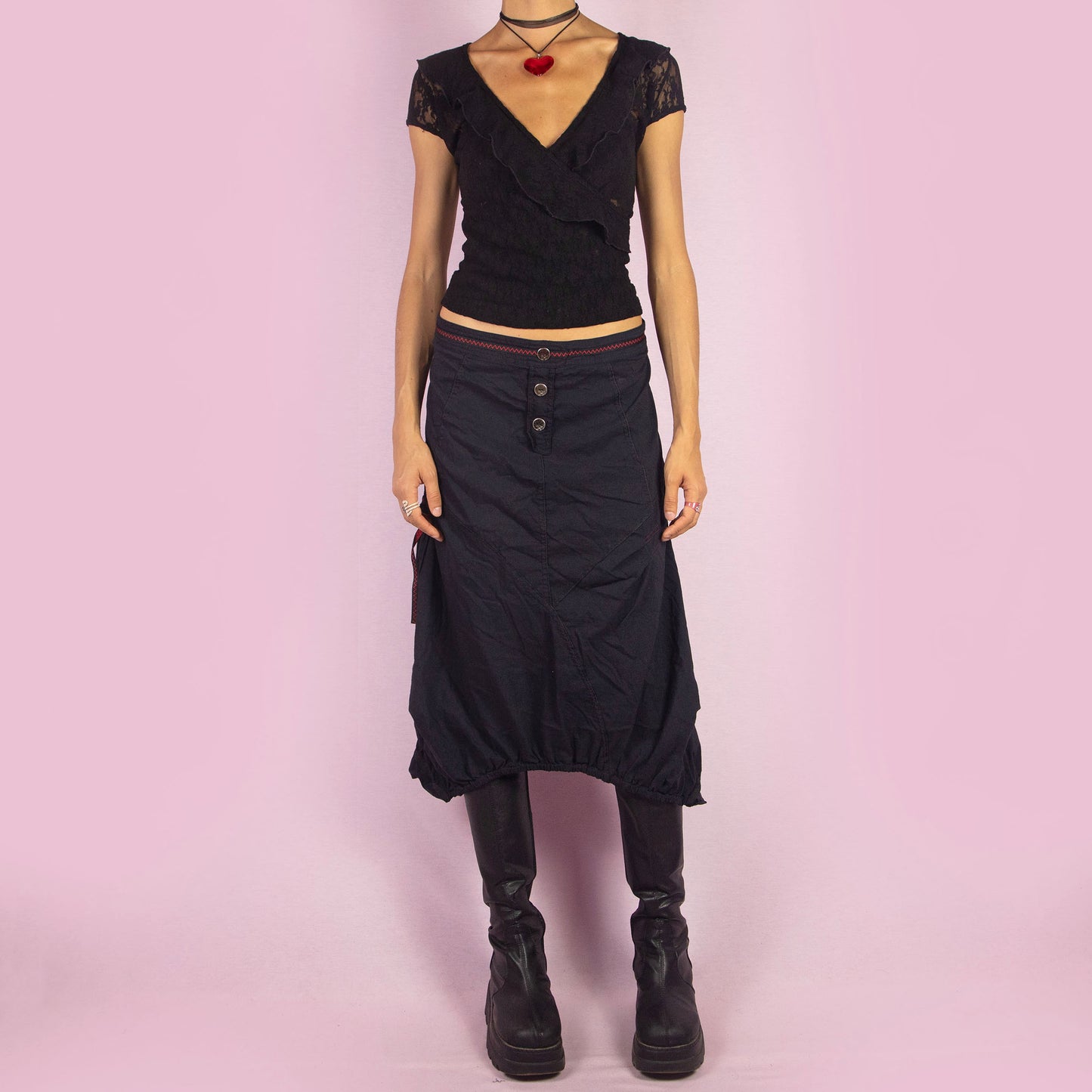 The Y2K Black Midi Balloon Skirt is a vintage 2000s piece featuring a button-front detail, stretchy fabric, and a side zipper closure. It includes pockets and has an avant-garde silhouette with a gathered hem, creating a balloon-style effect. Perfect for adding an edgy touch to casual outfits.