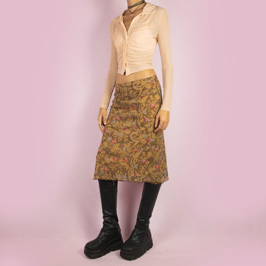 The Y2K Brown Floral Mesh Skirt is a vintage 2000s midi skirt featuring a semi-sheer overlay with an abstract floral pattern. It has an elastic waist and a stretchy fabric for a casual fit. Perfect for summer or spring outfits.