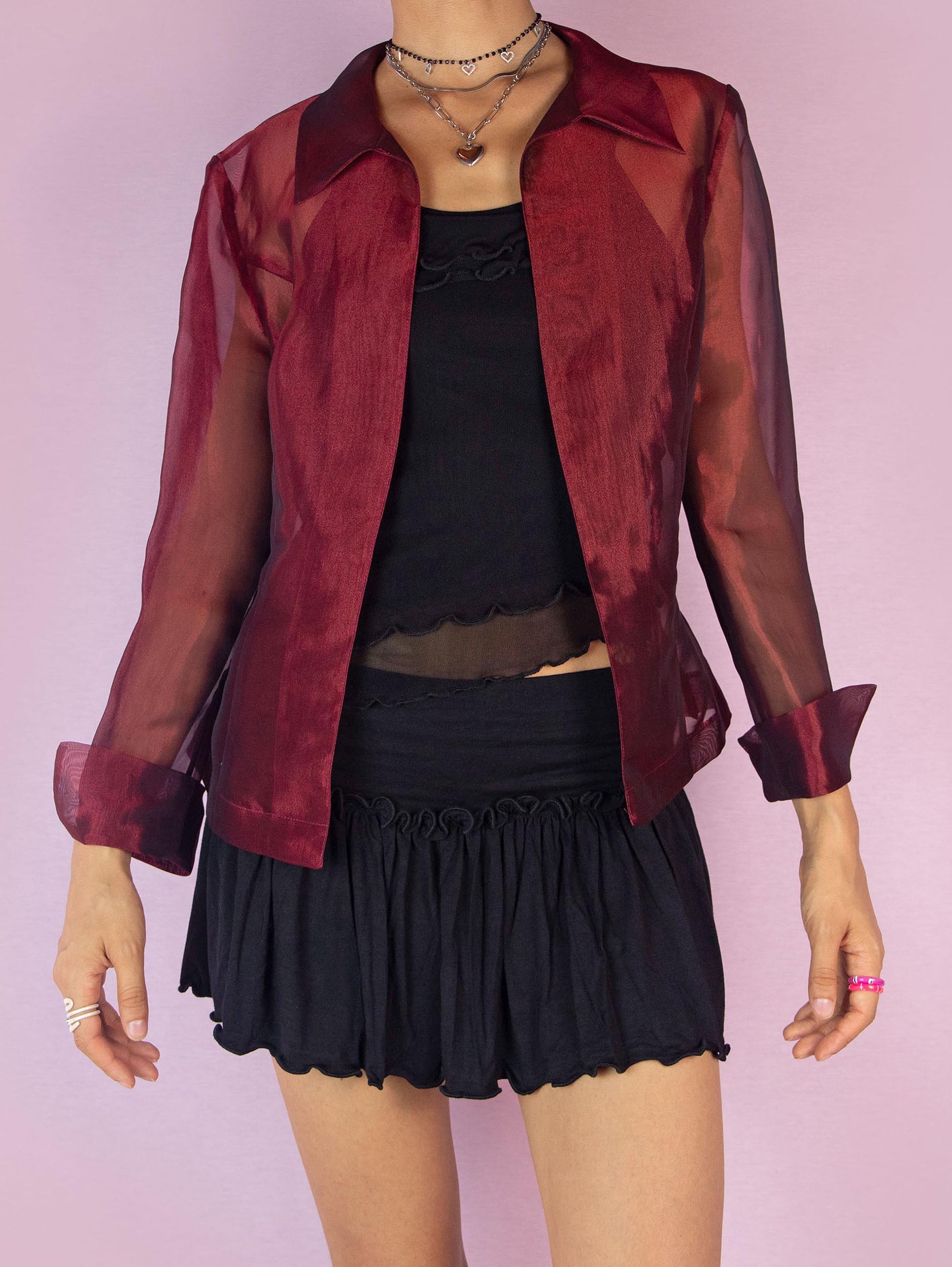 The Y2K Maroon Sheer Jacket is a vintage 2000s iridescent burgundy jacket featuring long sleeves, a pointed collar, and a tie waist. The lightweight, organza-style fabric gives it an elegant and sophisticated look, perfect for layering over evening or party outfits. Made in Spain.