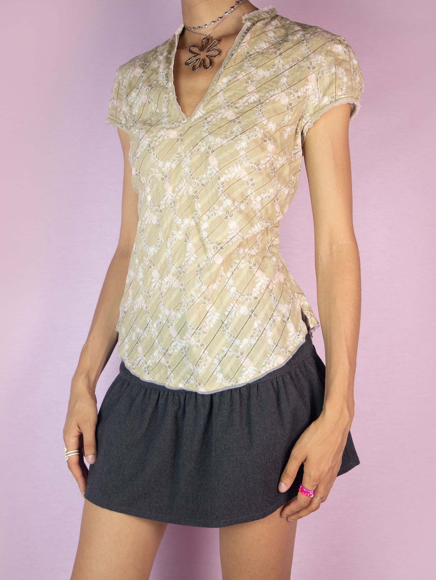 The Y2K Floral Print Cotton Blouse is a vintage 2000s beige, white, and pink top featuring a lightweight fabric, short sleeves, a v-neckline, and a relaxed fit, perfect for a casual summer look.