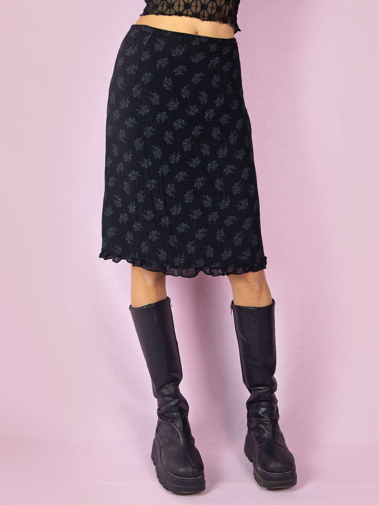 The Vintage 90s Black Floral Print Skirt is a high-waisted, straight pencil skirt with a ruffle hem and a side zipper closure. Made in France.