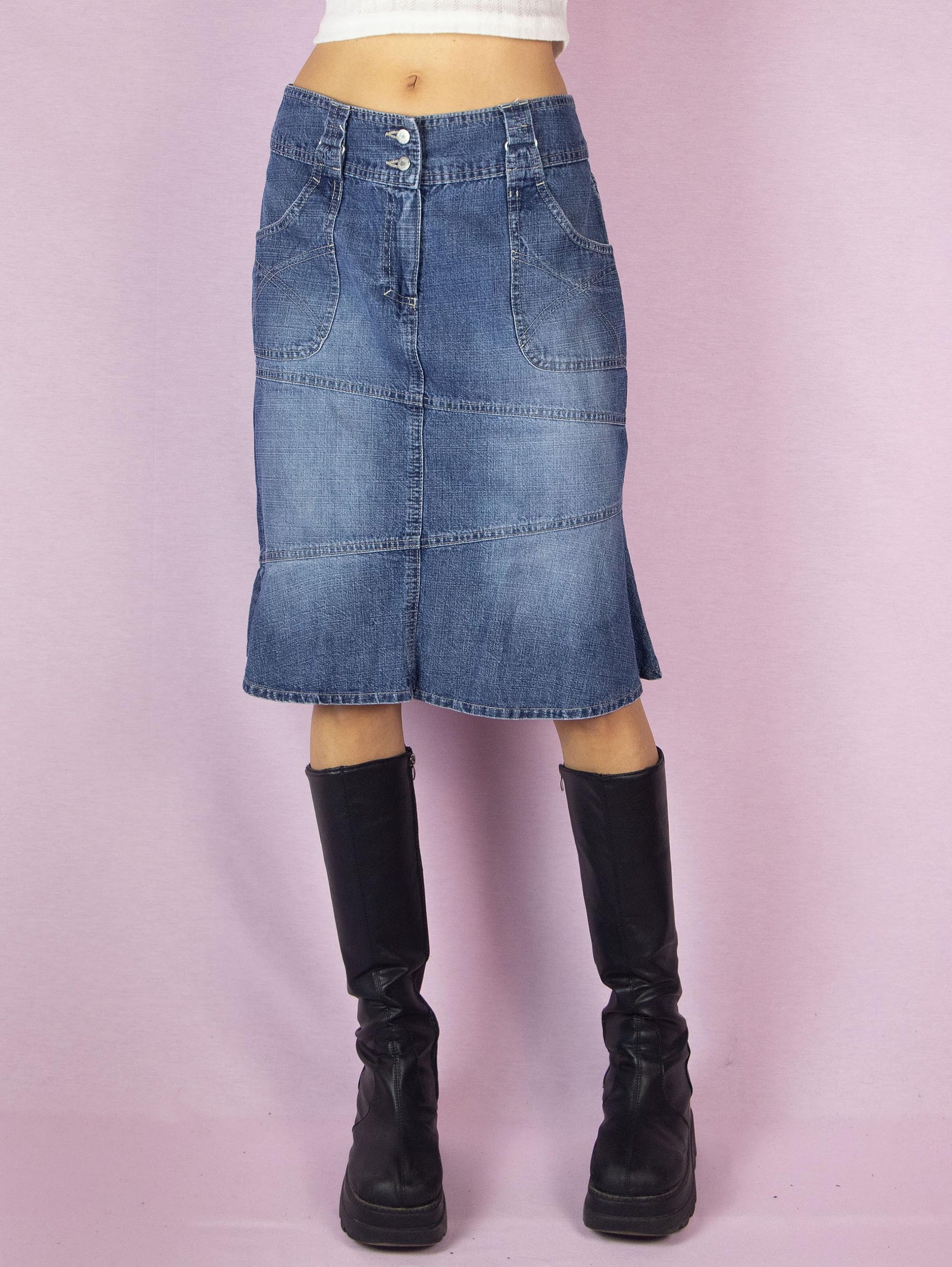 The Y2K Midi Trumpet Denim Skirt is a vintage 2000s paneled jean skirt in a streetwear grunge style with pockets, a front zipper closure, and a ruffle hem.