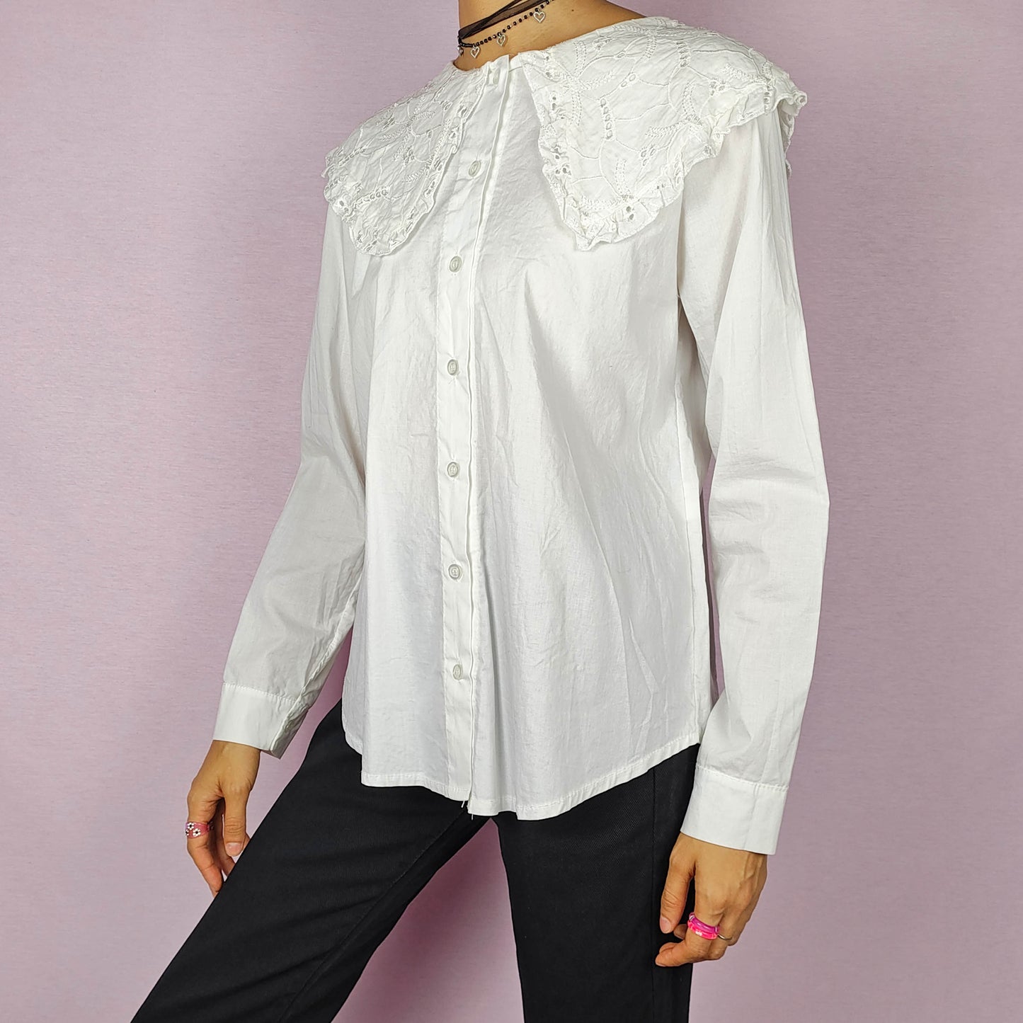 The Y2K Lace Collar White Blouse is a vintage 2000s shirt featuring an oversized lace collar in a delicate cream tone, long sleeves and a button-up front. Ideal for both casual and elegant formal wear.