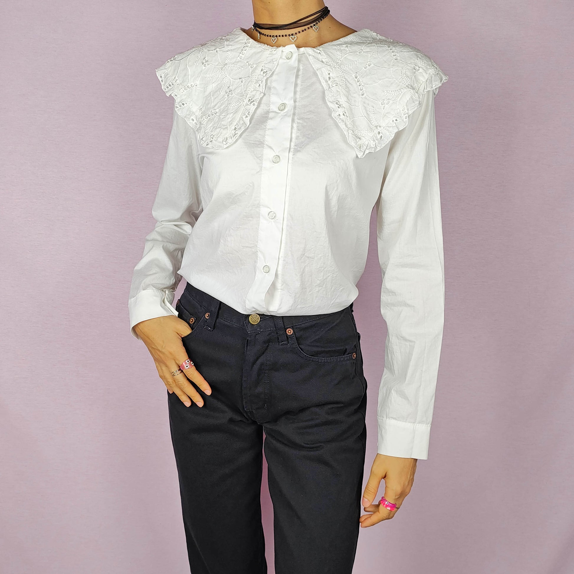 The Y2K Lace Collar White Blouse is a vintage 2000s shirt featuring an oversized lace collar in a delicate cream tone, long sleeves and a button-up front. Ideal for both casual and elegant formal wear.