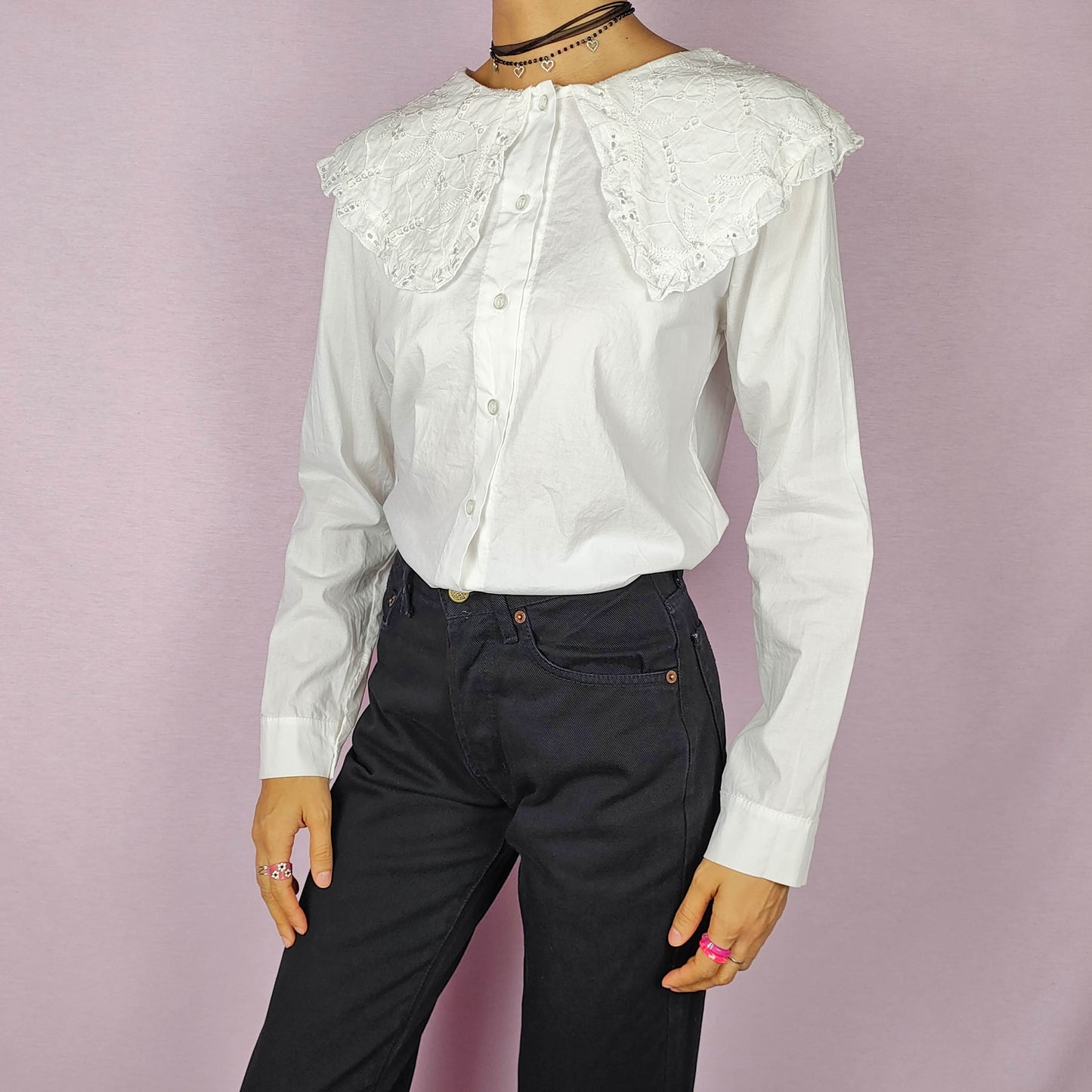 The Y2K Lace Collar White Blouse is a vintage 2000s shirt featuring an oversized lace collar in a delicate cream tone, long sleeves and a button-up front. Ideal for both casual and elegant formal wear.