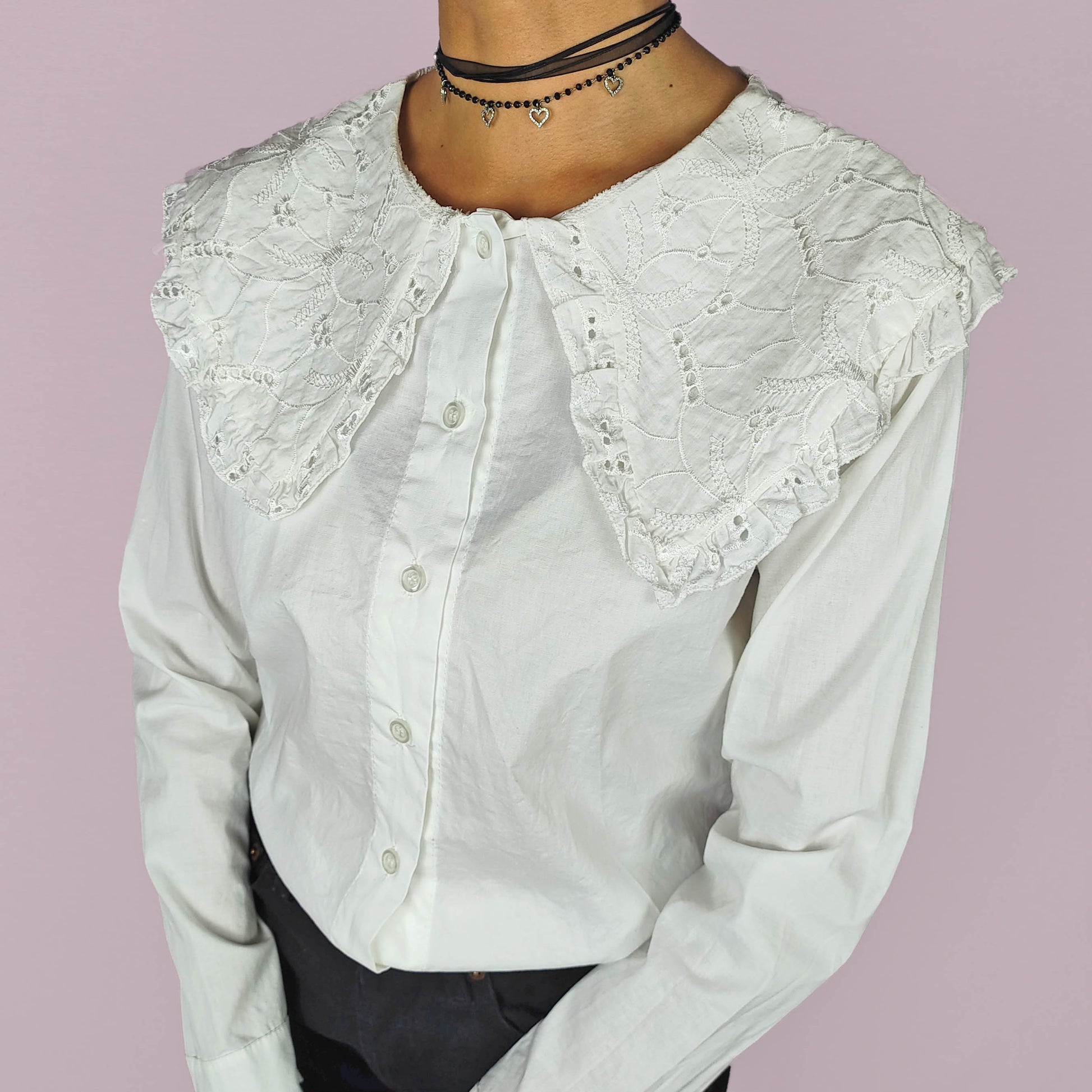 The Y2K Lace Collar White Blouse is a vintage 2000s shirt featuring an oversized lace collar in a delicate cream tone, long sleeves and a button-up front. Ideal for both casual and elegant formal wear.