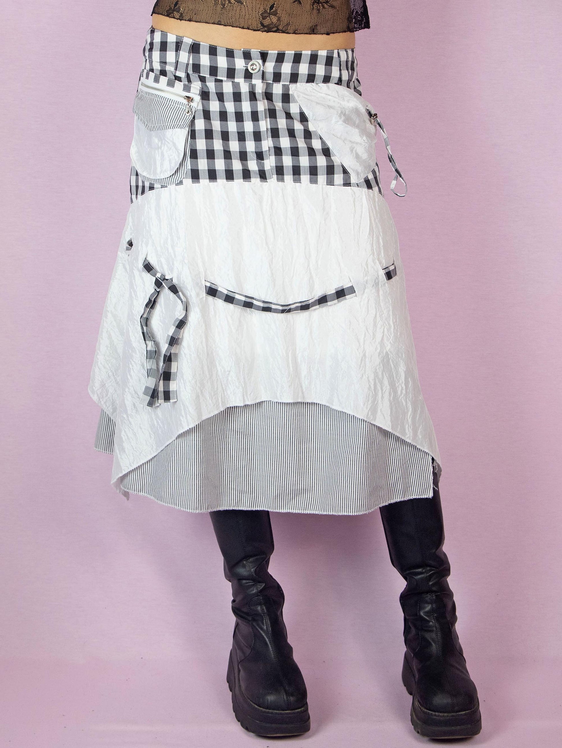 The Y2K Layered Handkerchief Midi Skirt is a vintage 2000s deconstructed subversive black and white skirt with a check plaid and stripe print, pockets, front zipper closure, and an asymmetrical hem.