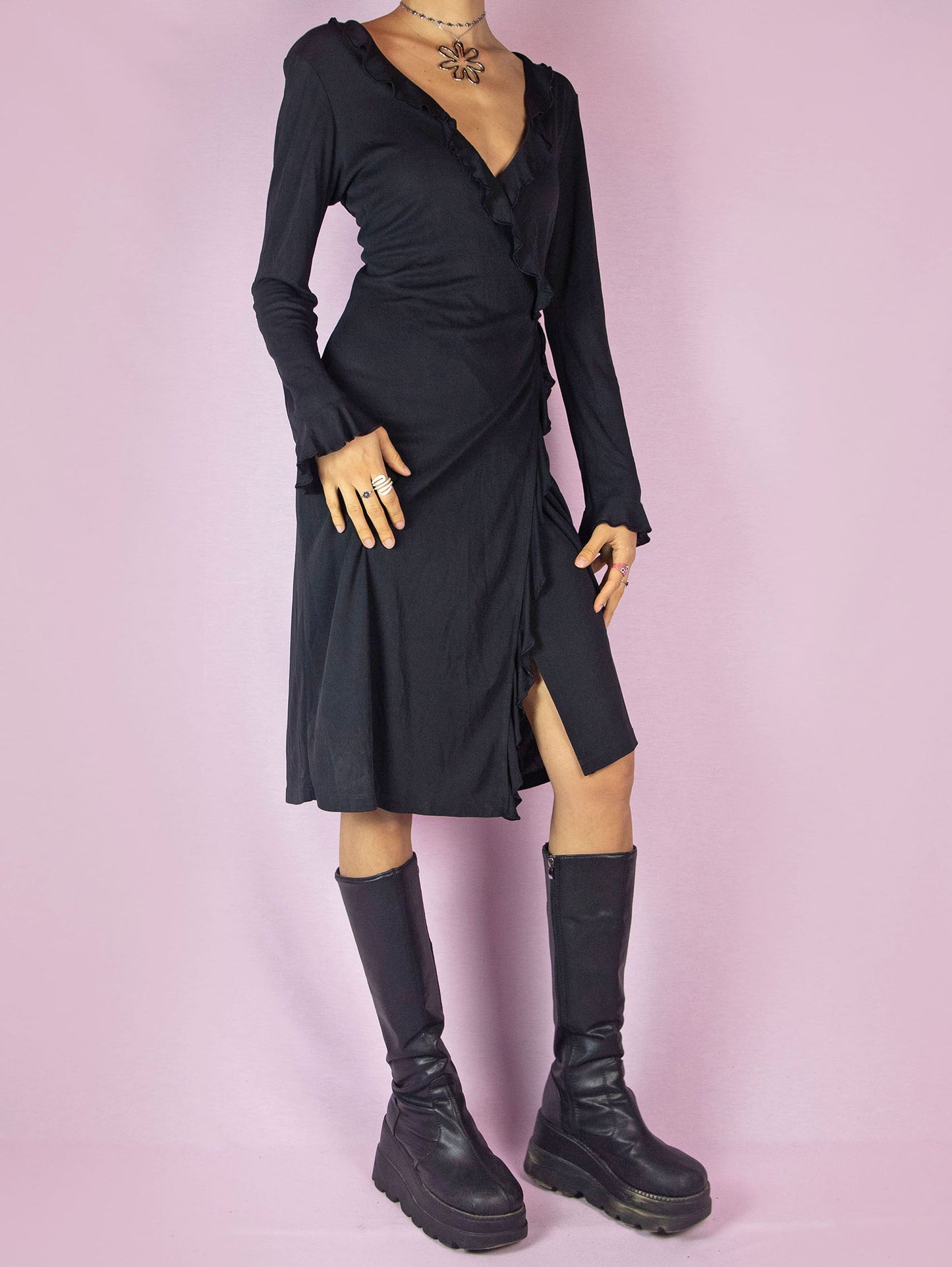 The Vintage 90s Black Ruffle Wrap Dress is a minimalist casual midi dress with long sleeves, a deep V-neckline, and is tied at the back.