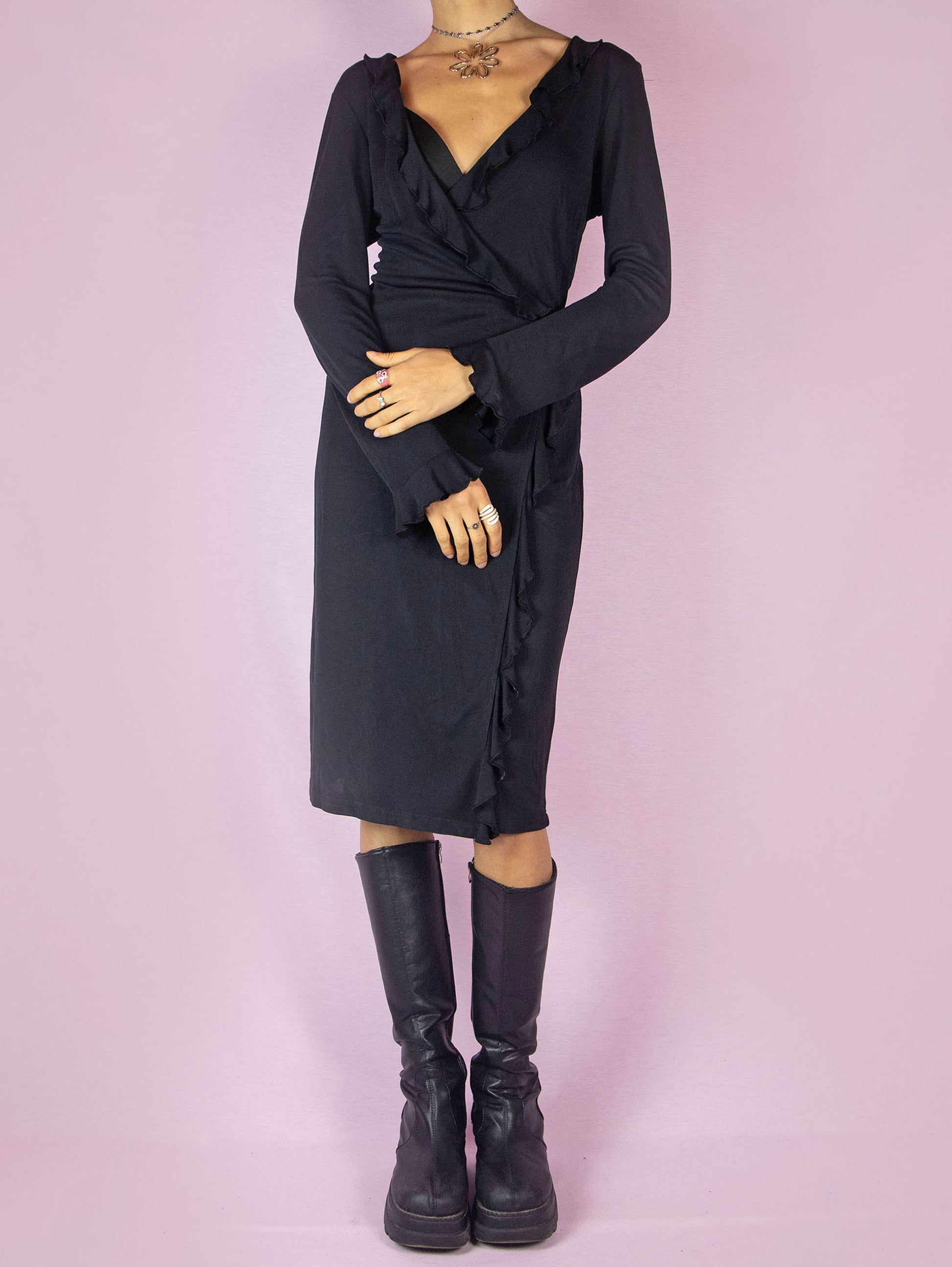 The Vintage 90s Black Ruffle Wrap Dress is a minimalist casual midi dress with long sleeves, a deep V-neckline, and is tied at the back.