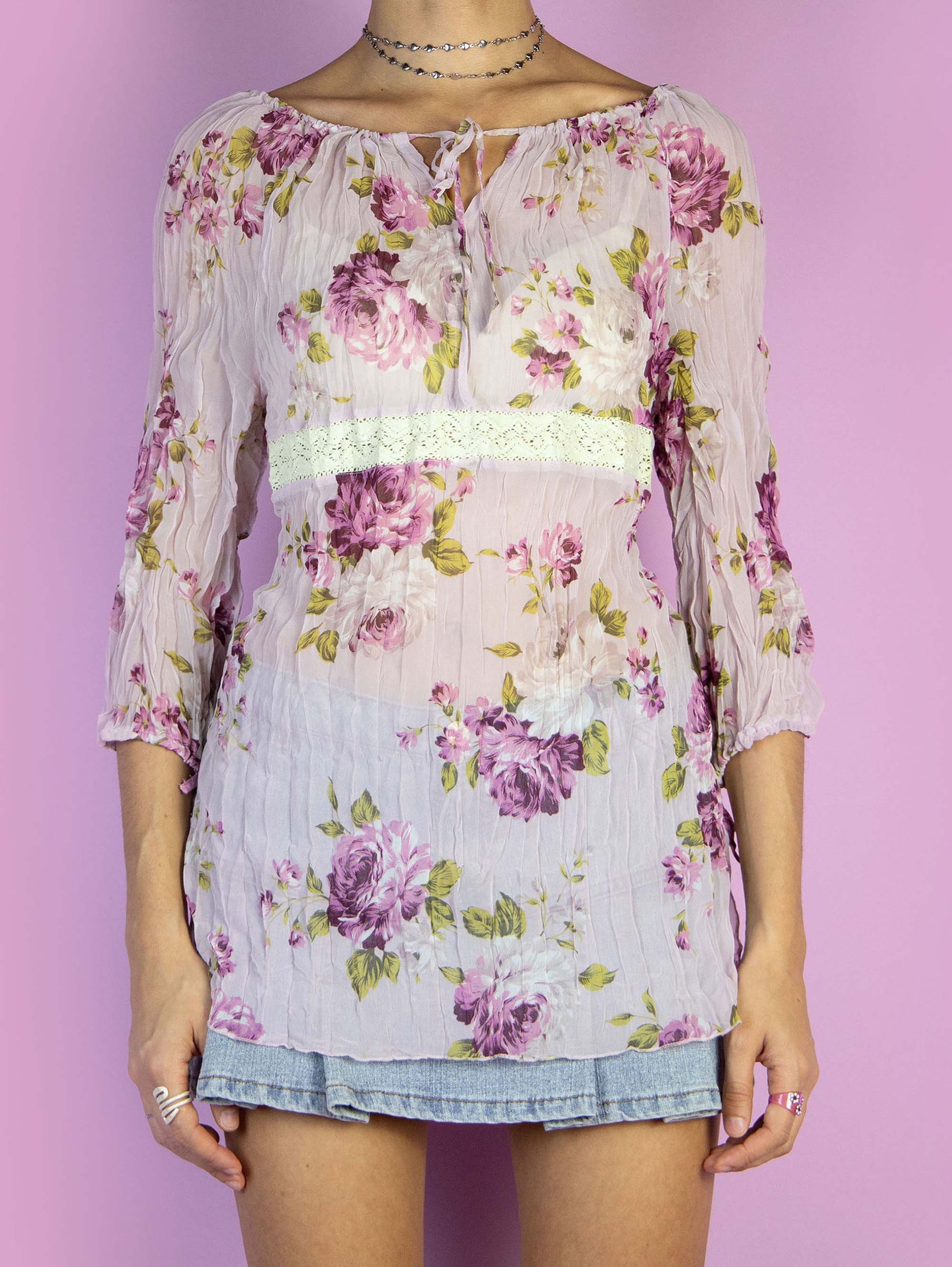 The Y2K Pink Floral Print Top is a vintage 2000s boho summer style semi-sheer blouse with half sleeves, and a tied neckline in the front.