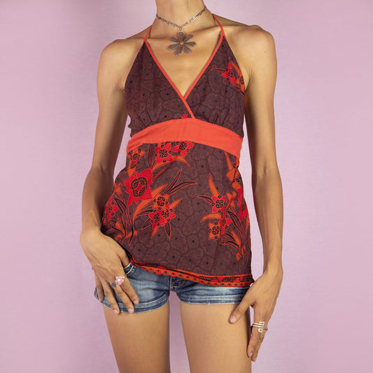 The Y2K Floral Halter Top is a vintage 2000s piece featuring a red and brown floral print, a flattering halter neckline, a tie neck for adjustable fit, and a smocked back. This lightweight and breathable top is perfect for summer days or boho-inspired looks.