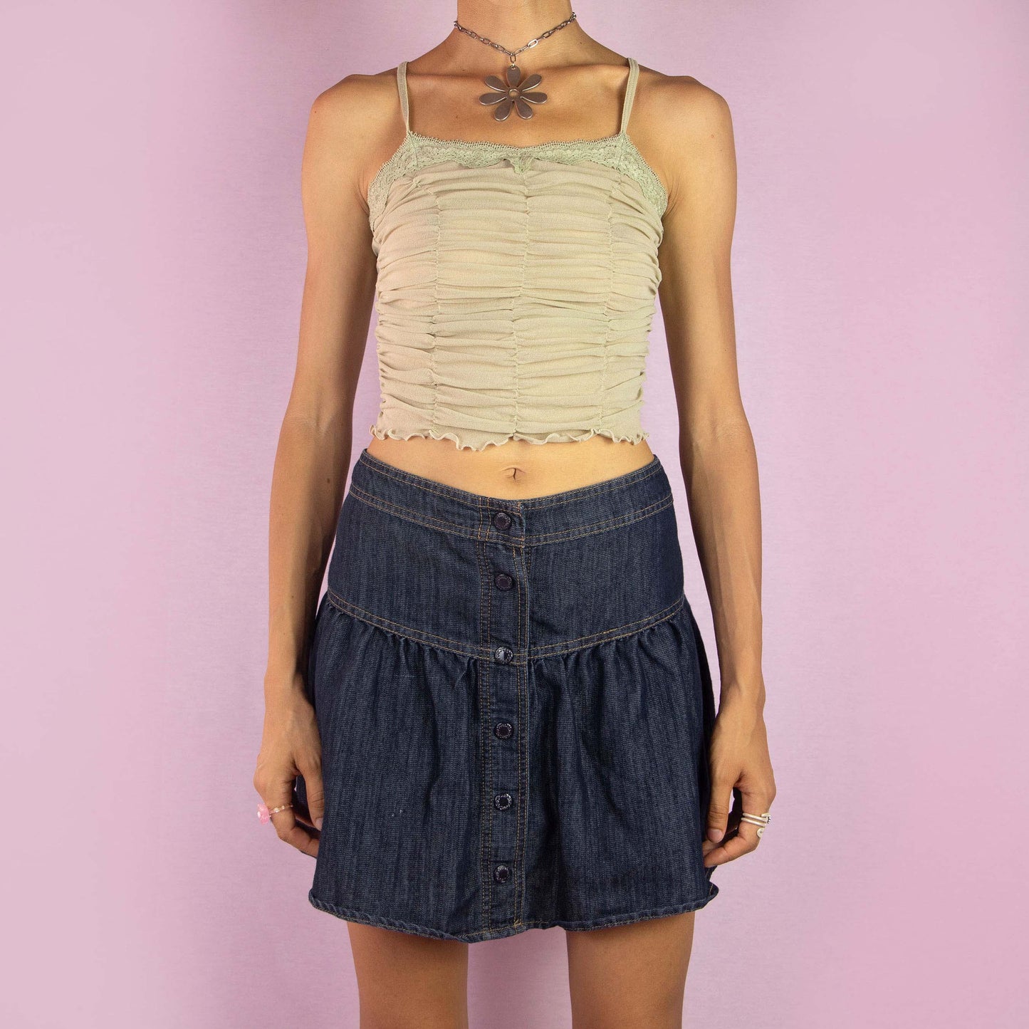 The Y2K Denim Flare Mini Skirt is a vintage 2000s piece featuring a mid-rise fit and a flared A-line silhouette. Made from dark-wash denim, this skirt showcases a tiered design with button-up detailing along the front. Ideal for casual wear and summer outings.