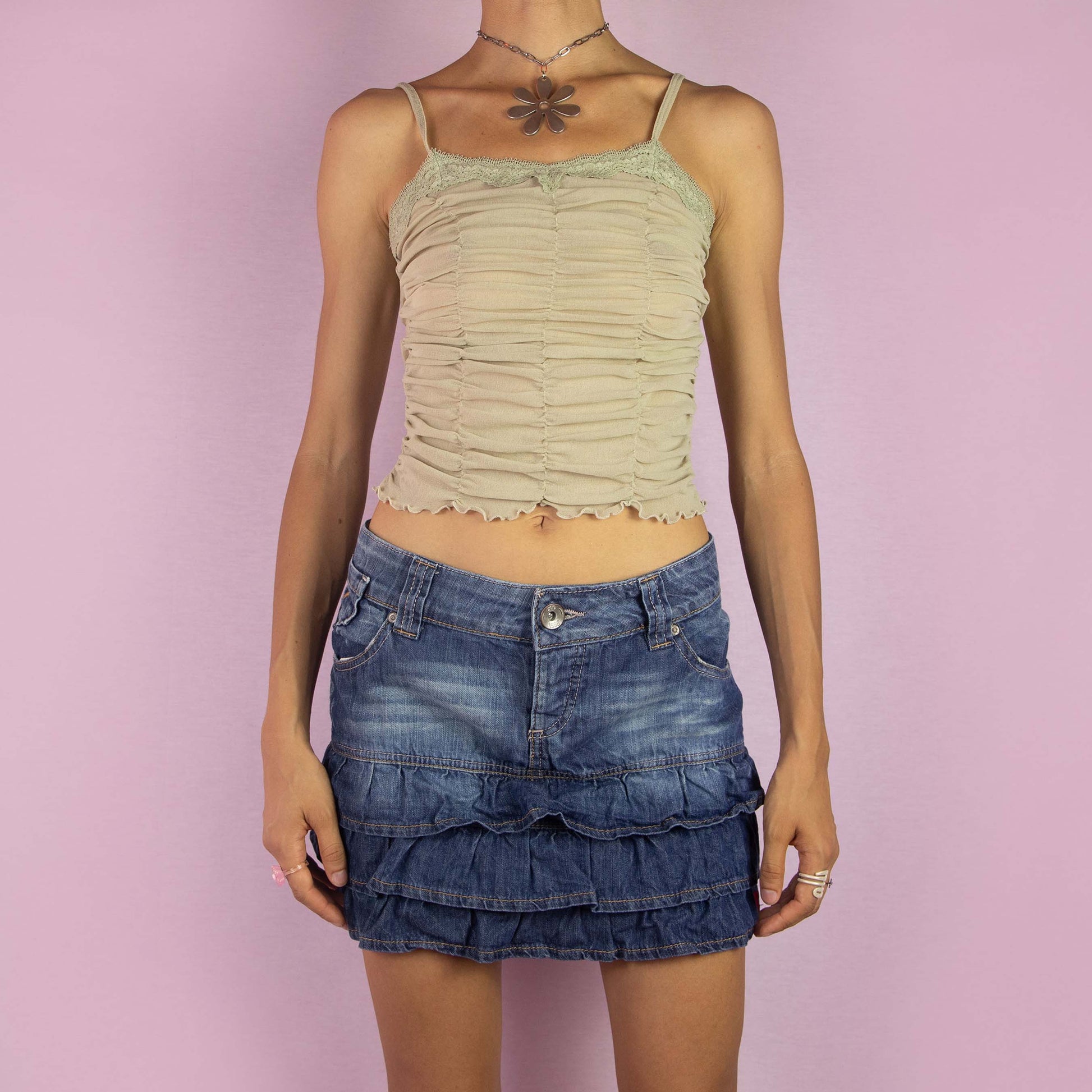 The Y2K Denim Ruffle Mini Skirt is a vintage 2000s piece featuring a low-rise fit and a playful tiered ruffle design. Made from medium-wash denim, the skirt has a faded effect, front and back pockets, and a button closure. Perfect for casual wear and summer outings.