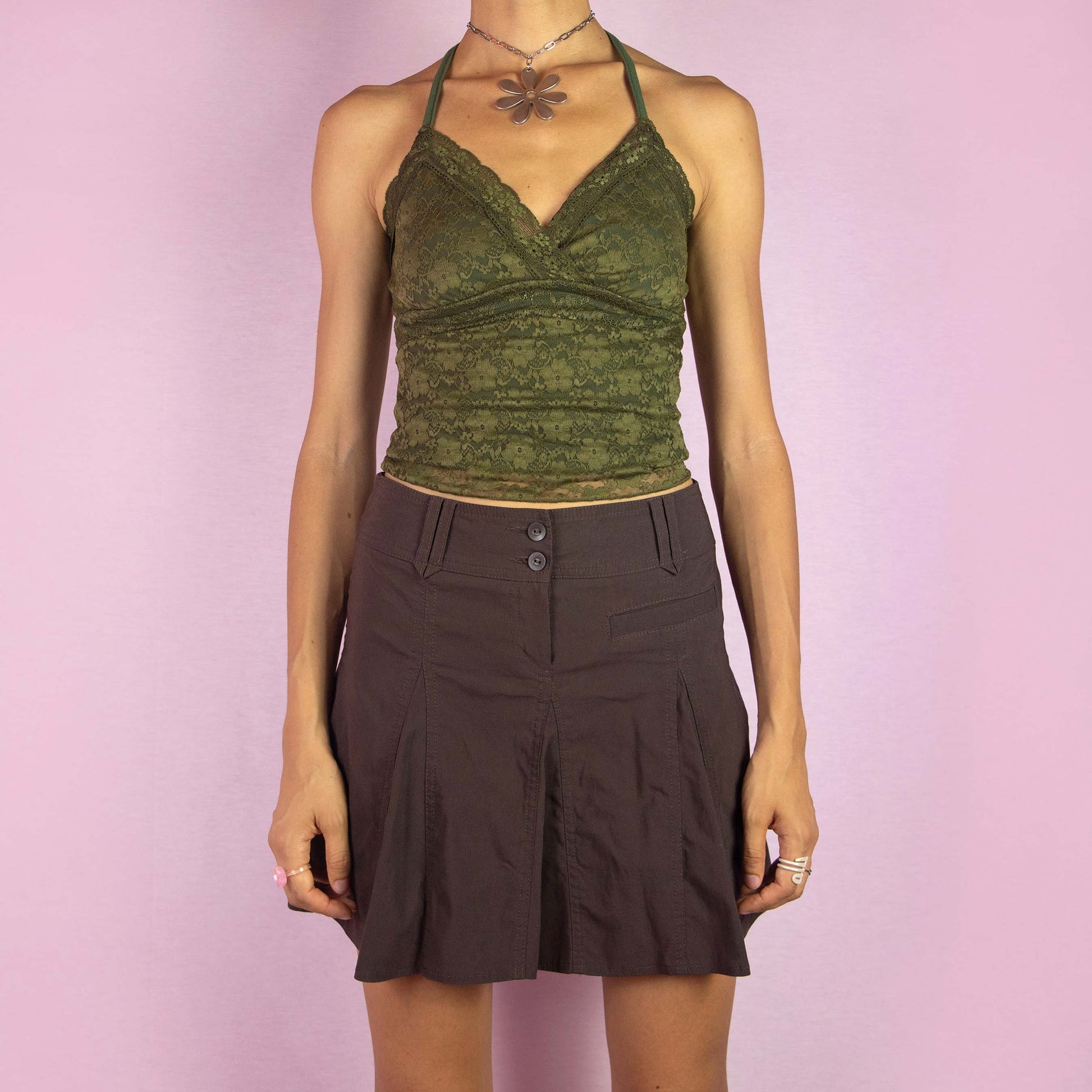 The Y2K Flare Brown Mini Skirt is a vintage 2000s piece featuring a high-rise fit, stretchy fabric, and a flared A-line godet silhouette. The skirt includes pleated detailing along the front and back, with a double-button and zipper closure. Ideal for casual wear and summer outings.