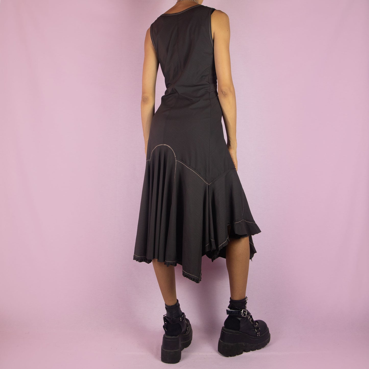 The Y2K Asymmetric Brown Midi Dress is a vintage 2000s sleeveless piece with a stretchy fabric and a pointed, asymmetric hemline. Its flowy silhouette and minimalist design make it perfect for casual wear and evening events.