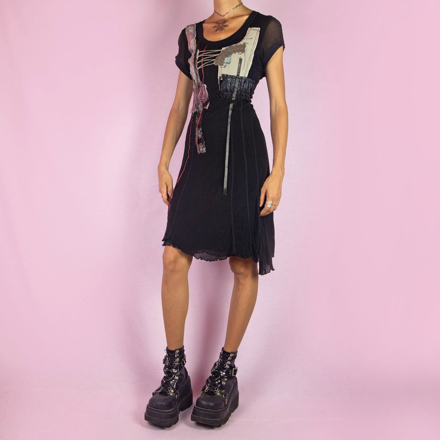 The Y2K Black Knit Dress is a vintage 2000s layered mini dress featuring a stretchy silk-knit fabric and short sleeves. Adorned with patchwork details, lace-up accents, and raw edges, it has an eclectic, whimsical look. The unique blend of textures and asymmetrical lines make it perfect for casual outings and evening event. Made in Spain.