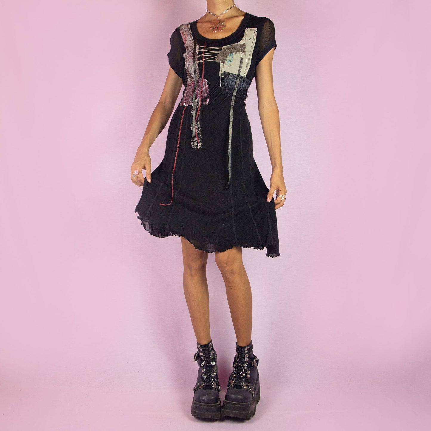 The Y2K Black Knit Dress is a vintage 2000s layered mini dress featuring a stretchy silk-knit fabric and short sleeves. Adorned with patchwork details, lace-up accents, and raw edges, it has an eclectic, whimsical look. The unique blend of textures and asymmetrical lines make it perfect for casual outings and evening event. Made in Spain.