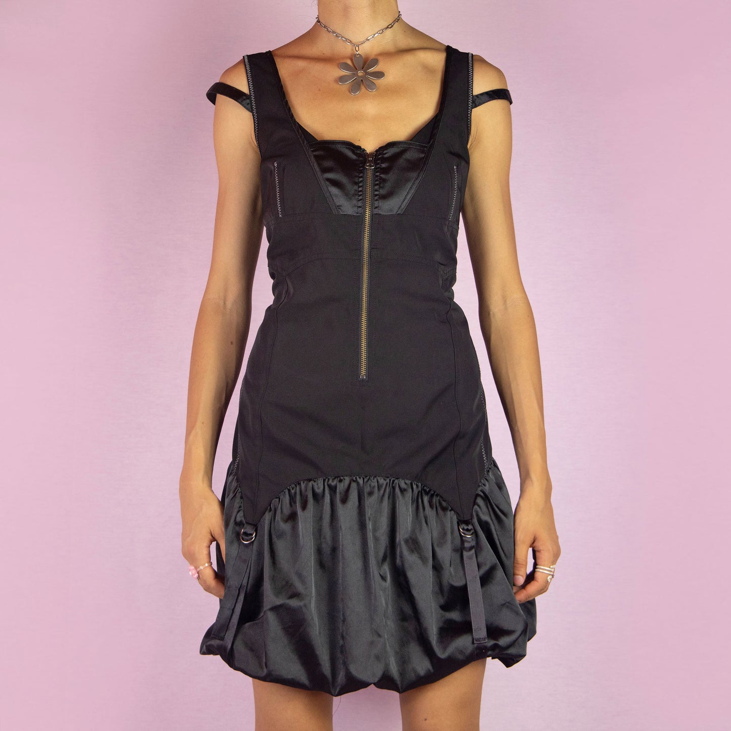 The Y2K Black Bubble Mini Dress is a vintage 2000s piece featuring a fitted bodice with a satin finish and front zipper. It has double straps and a distinctive bubble hemline with ruching and buckle details. Its structured design and sleek silhouette make it ideal for evening events and nights out.