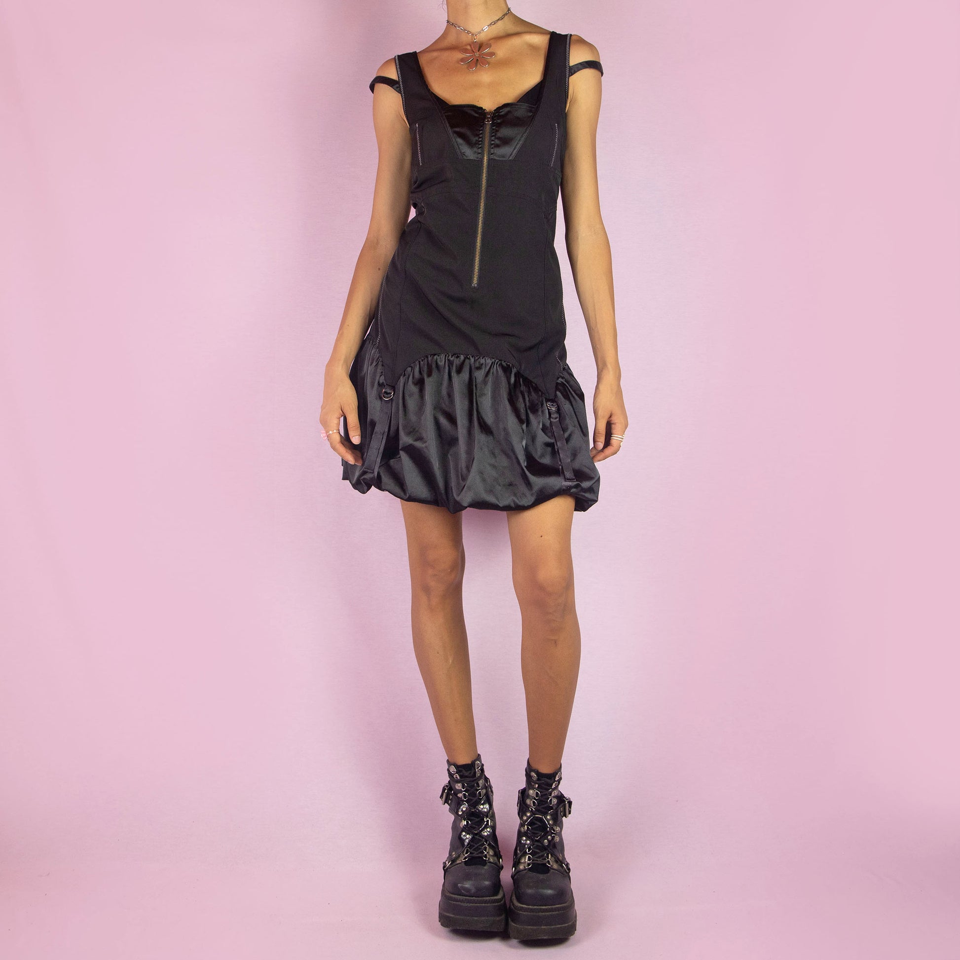 The Y2K Black Bubble Mini Dress is a vintage 2000s piece featuring a fitted bodice with a satin finish and front zipper. It has double straps and a distinctive bubble hemline with ruching and buckle details. Its structured design and sleek silhouette make it ideal for evening events and nights out.