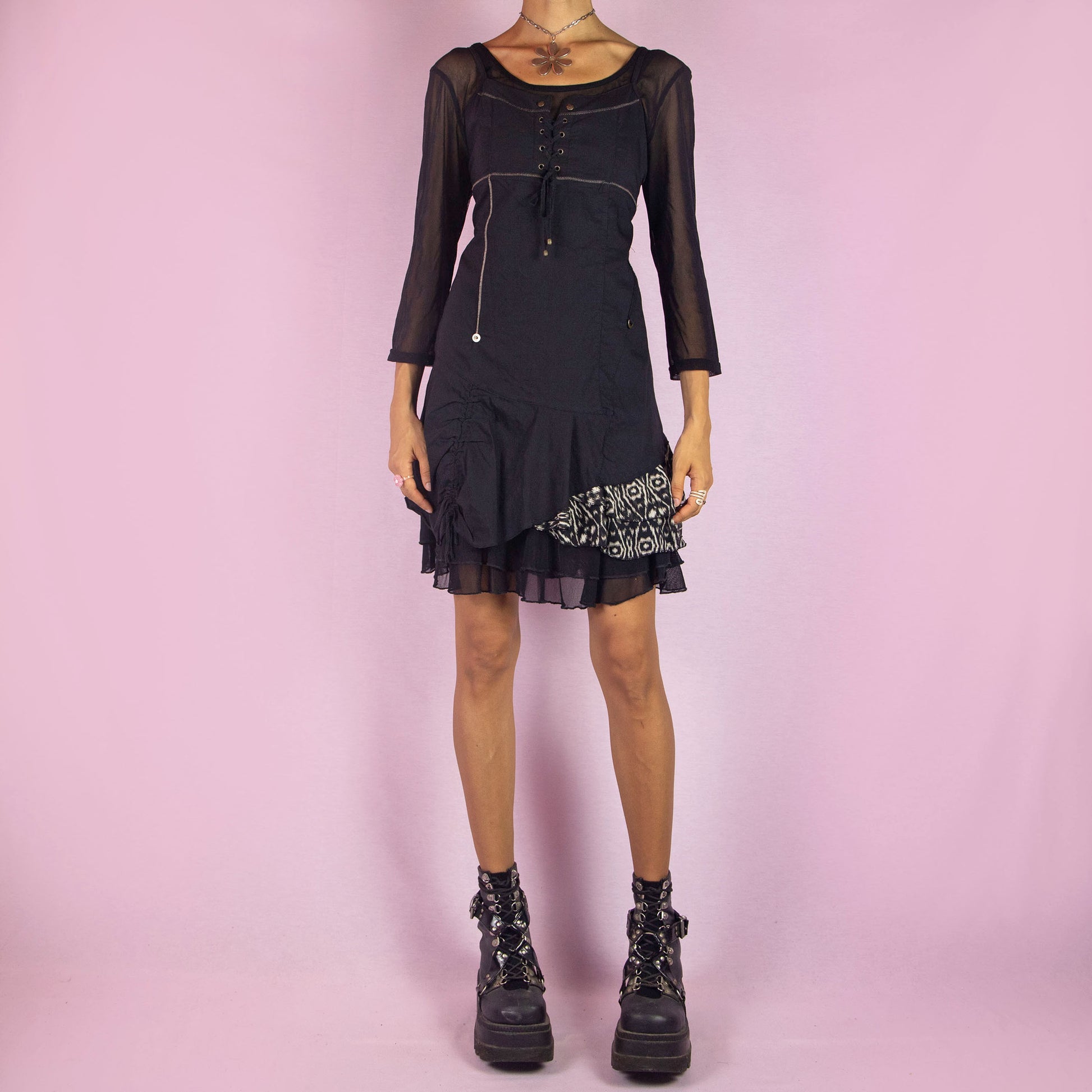 The Y2K Black Asymmetric Mesh Dress is a vintage 2000s mini dress featuring a scoop neckline, three-quarter sheer mesh sleeves, and a stretchy fabric. It has a lace-up bodice, side zipper closure, and an asymmetric hemline with gathered details and a printed panel. The layered mesh underlay gives it a whimsical touch, making it perfect for parties and night events.