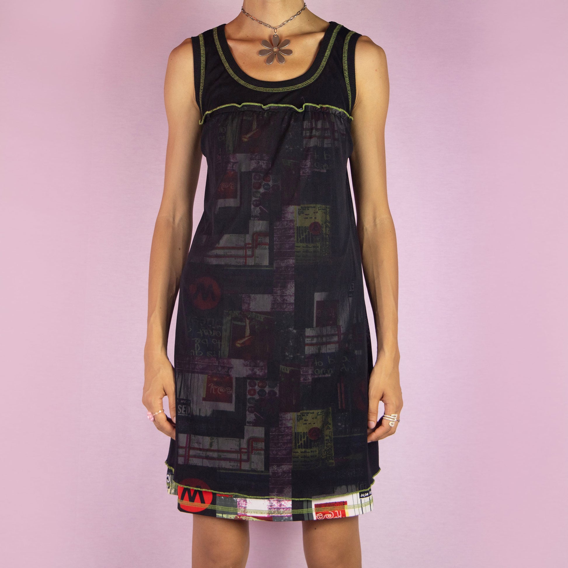 The Y2K Black Sleeveless Mesh Dress is a vintage 2000s mini dress featuring a scoop neckline, relaxed fit, and lightweight mesh fabric. The dress is adorned with abstract prints and neon green stitching along the neckline and hem. Its layered design and playful details make it perfect for casual summer outings.