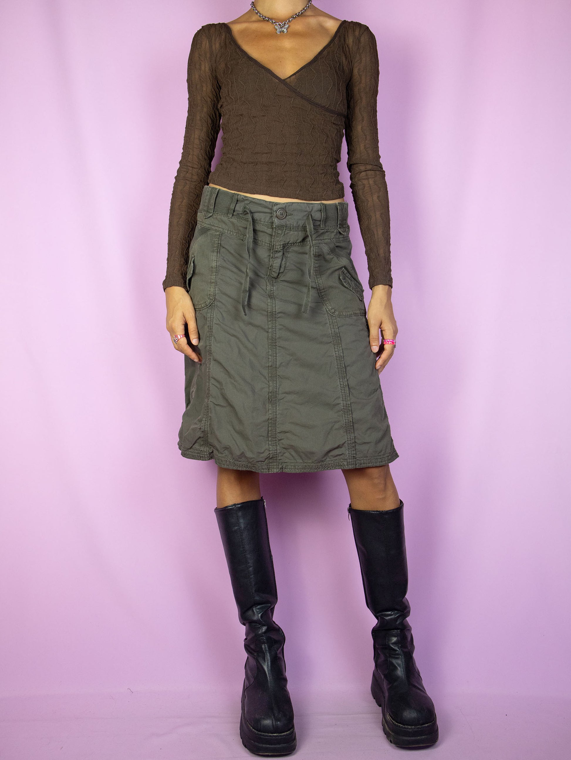 The Y2K Subversive Khaki Cargo Skirt is a vintage dark khaki green flared skirt with pockets and a front zipper closure. A gorgeous utility cargo style gorpcore grunge midi skirt from the 2000s.