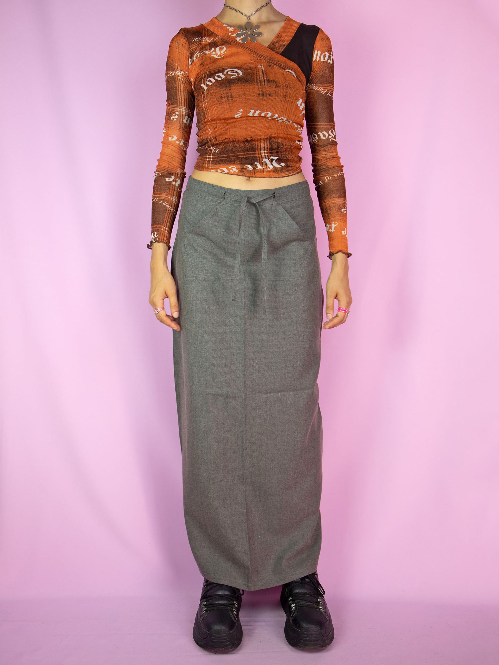 The Vintage 90s Gray Maxi Skirt is a slit-back skirt in gray that ties in the front, featuring a pocket and back zipper closure. Cyber grunge 1990s cargo midi skirt.