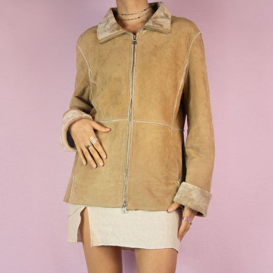 The Y2K Guess Leather Jacket is a vintage 2000s piece featuring a real beige suede leather exterior and a plush faux fur lining for added warmth. This jacket includes a zip-up front, a fold-over collar, and faux fur trim at the cuffs. Perfect for casual wear during colder seasons.