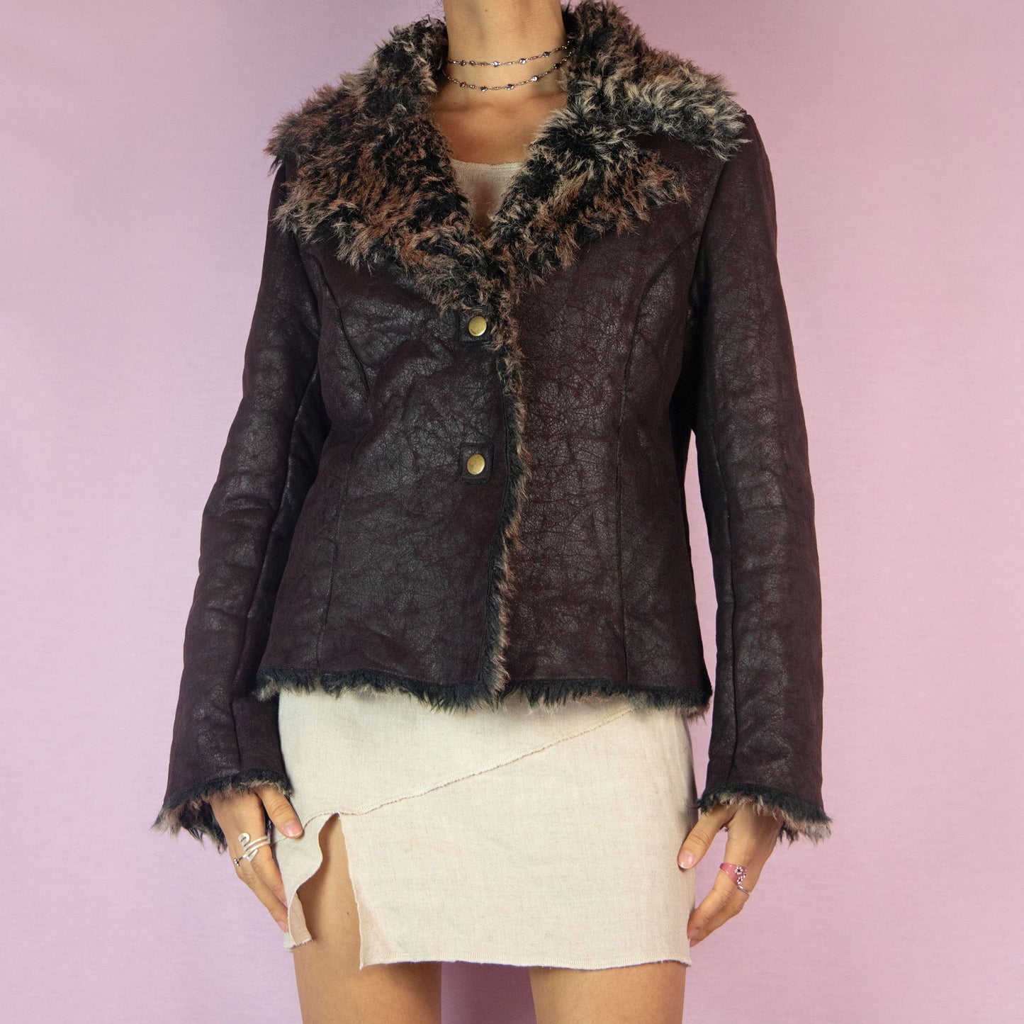 The Y2K Faux Leather Fur Jacket is a vintage 2000s piece featuring a distressed faux leather exterior and faux fur lining throughout. With a fitted silhouette, plush faux fur-trimmed collar and cuffs, and snap button closure, this jacket is both cozy and stylish. Perfect for night outings or parties.