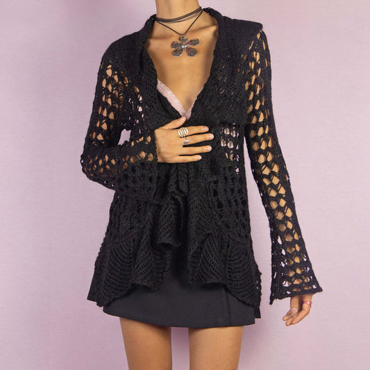 The Y2K Black Ruffle Crochet Cardigan is a vintage 2000s piece featuring an open-knit crochet design with an open front, flared sleeves, and a flowy ruffled hem. This lightweight cardigan is perfect for layering, adding a boho touch to any casual or party outfit.