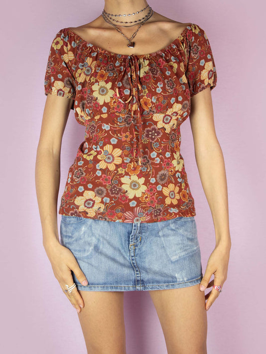 The Y2K Print Mesh Milkmaid Top is a vintage 2000s floral graphic earthy red blouse with short puff sleeves, an elasticized neckline that can be worn off-the-shoulder or on-the-shoulder and has a gathered detail at the bust with a tie at the center. Perfect for a casual summer look.