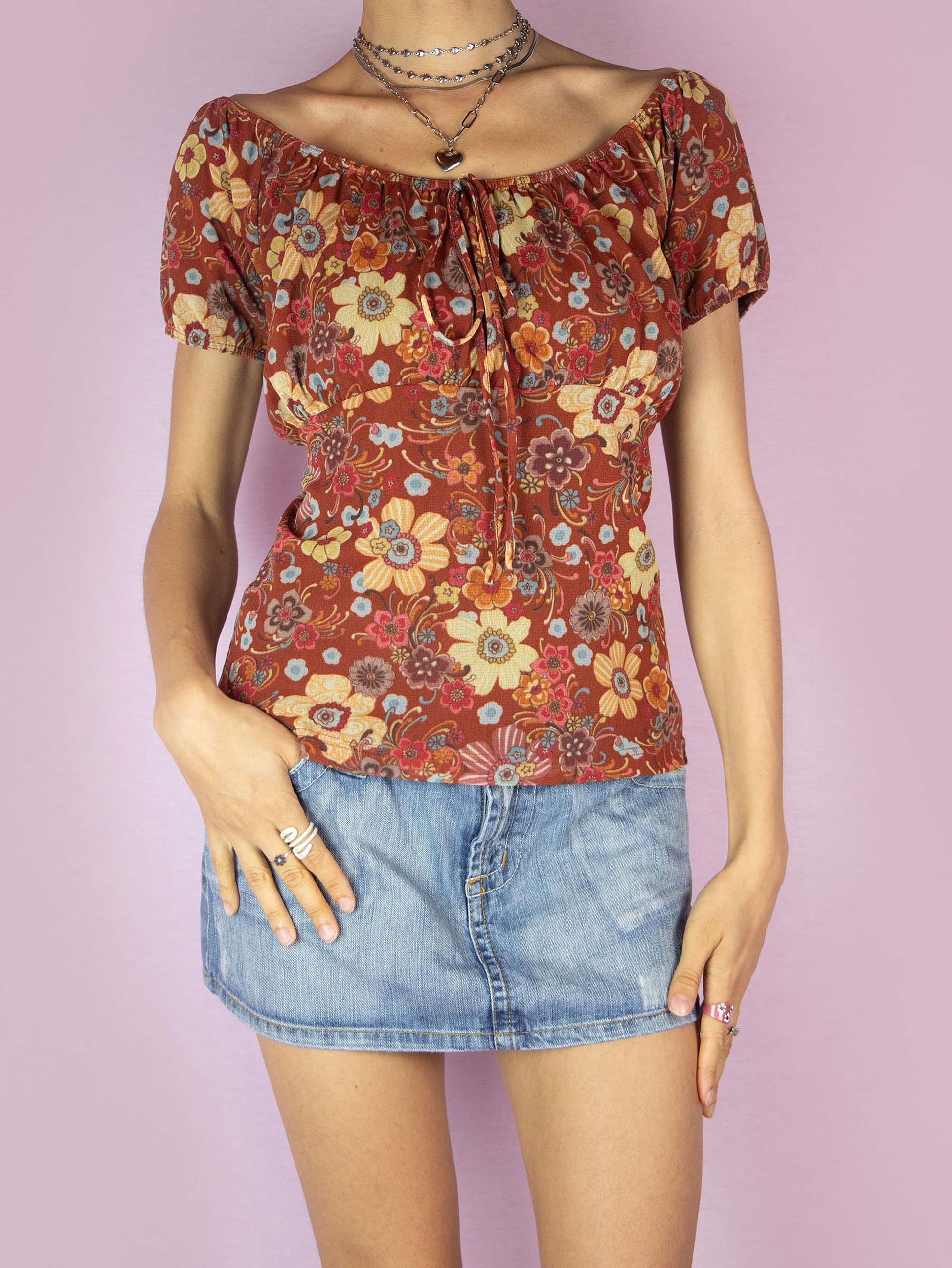 The Y2K Print Mesh Milkmaid Top is a vintage 2000s floral graphic earthy red blouse with short puff sleeves, an elasticized neckline that can be worn off-the-shoulder or on-the-shoulder and has a gathered detail at the bust with a tie at the center. Perfect for a casual summer look.