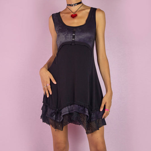 The Y2K Sleeveless Black Mini Dress is a vintage 2000s piece featuring a sleeveless design with a scoop neckline. Made from stretchy fabric, this dress has a buttoned bodice detail and a subtle tie-dye print across the top. The layered ruffle hem with mesh accents and adjustable drawstring ties adds a customizable fit. Perfect for summer casual outings or night parties.