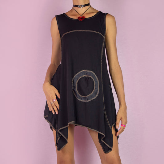 The Y2K Black Asymmetric Sleeveless Top is a vintage 2000s shirt featuring a flowy, oversized silhouette with bold circular stitched detailing. Made from stretchy fabric, this top has an asymmetric hemline, perfect for summer casual wear or layering for a unique, statement look. Made in Italy.