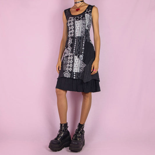 The Y2K Black Mesh Sleeveless Dress is a vintage 2000s piece featuring an abstract patchwork design with various patterns in contrasting shades of black and white. Made from stretchy fabric with printed mesh details, this mini dress offers a unique, asymmetrical hemline, perfect for casual summer wear or layered looks.