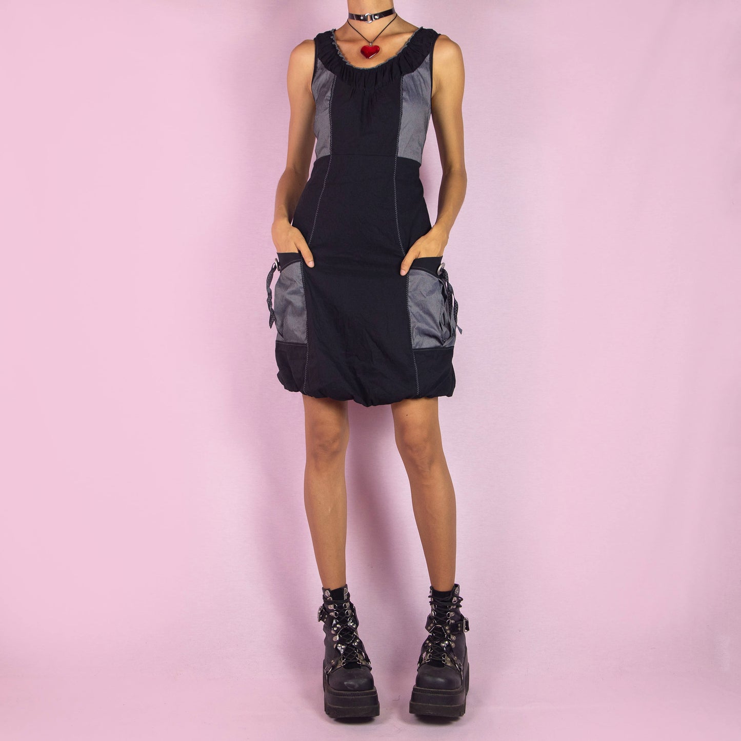 The Y2K Mini Black Bubble Dress is a vintage 2000s piece featuring a sleeveless design and a bubble hemline. Made from a lightweight, stretchy fabric, this dress is accented with contrast side panels and front pockets. Perfect for casual summer outings or party wear.