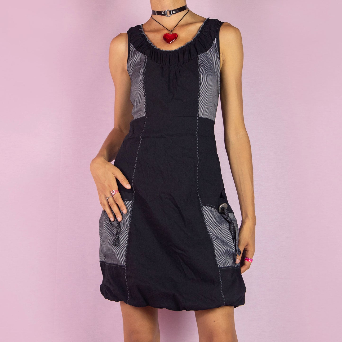 The Y2K Mini Black Bubble Dress is a vintage 2000s piece featuring a sleeveless design and a bubble hemline. Made from a lightweight, stretchy fabric, this dress is accented with contrast side panels and front pockets. Perfect for casual summer outings or party wear.