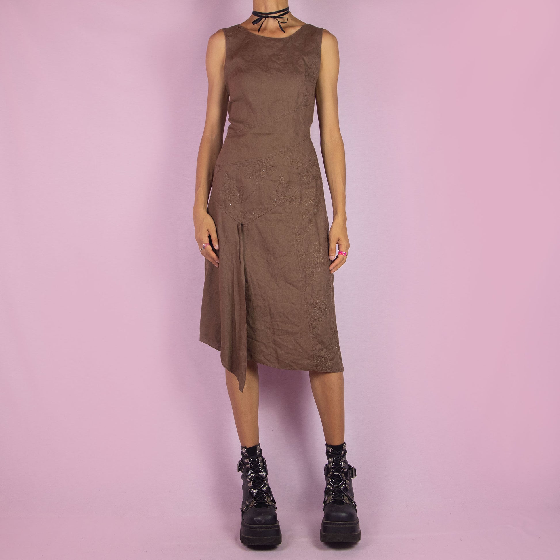 The Y2K Brown Asymmetric Sleeveless Dress is a vintage 2000s midi piece featuring floral embroidered detailing and a layered design. Made from a linen-like fabric, it has a side zipper closure. The unique asymmetric hemline and sleeveless silhouette make it perfect for casual wear, elegant parties, or summer outings.