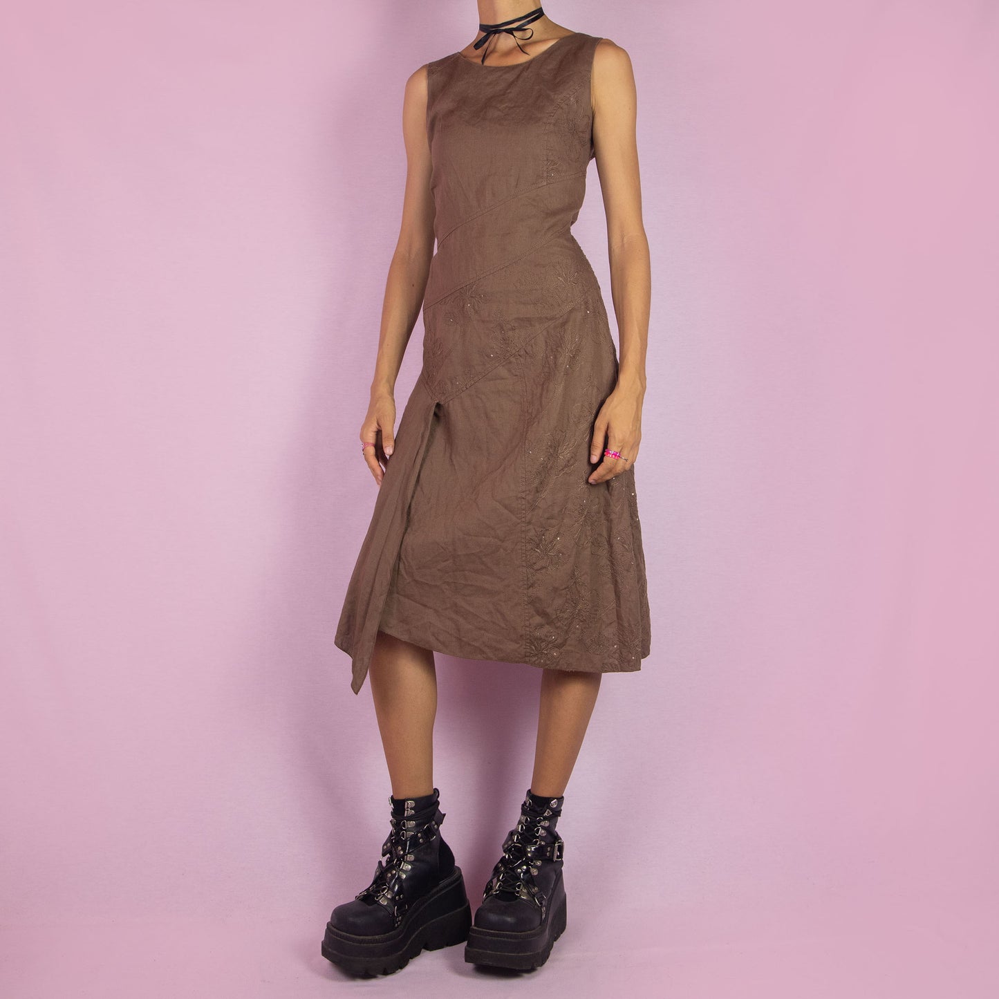 The Y2K Brown Asymmetric Sleeveless Dress is a vintage 2000s midi piece featuring floral embroidered detailing and a layered design. Made from a linen-like fabric, it has a side zipper closure. The unique asymmetric hemline and sleeveless silhouette make it perfect for casual wear, elegant parties, or summer outings.