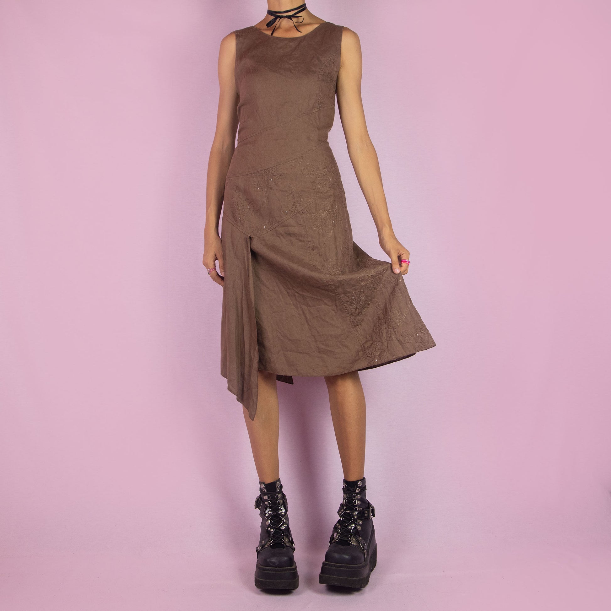 The Y2K Brown Asymmetric Sleeveless Dress is a vintage 2000s midi piece featuring floral embroidered detailing and a layered design. Made from a linen-like fabric, it has a side zipper closure. The unique asymmetric hemline and sleeveless silhouette make it perfect for casual wear, elegant parties, or summer outings.