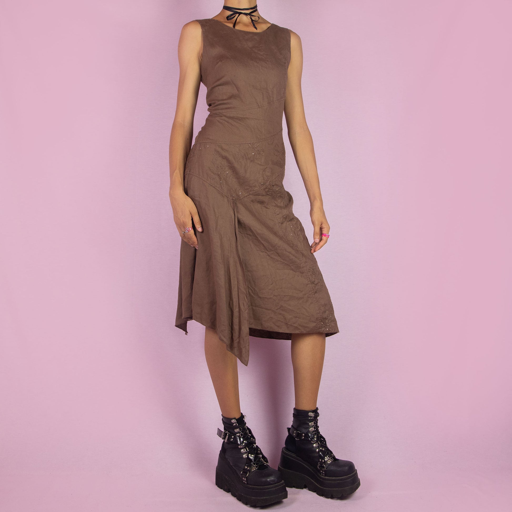 The Y2K Brown Asymmetric Sleeveless Dress is a vintage 2000s midi piece featuring floral embroidered detailing and a layered design. Made from a linen-like fabric, it has a side zipper closure. The unique asymmetric hemline and sleeveless silhouette make it perfect for casual wear, elegant parties, or summer outings.