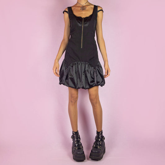 The Y2K Black Bubble Mini Dress is a vintage 2000s piece featuring a fitted bodice with a satin finish and front zipper. It has double straps and a distinctive bubble hemline with ruching and buckle details. Its structured design and sleek silhouette make it ideal for evening events and nights out.