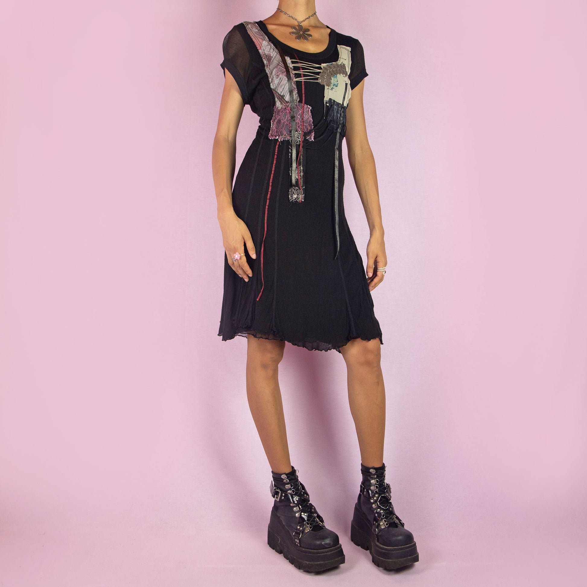 The Y2K Black Knit Dress is a vintage 2000s layered mini dress featuring a stretchy silk-knit fabric and short sleeves. Adorned with patchwork details, lace-up accents, and raw edges, it has an eclectic, whimsical look. The unique blend of textures and asymmetrical lines make it perfect for casual outings and evening event. Made in Spain.