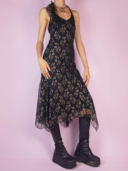 The Y2K Black Lace Asymmetrical Midi Dress is a vintage 2000s piece featuring a halter neck design and intricate golden floral lace detailing over a delicate mesh fabric. The dress is accented with ruffles along the neckline, adding a touch of romance and elegance. Perfect for a night out or special occasion.