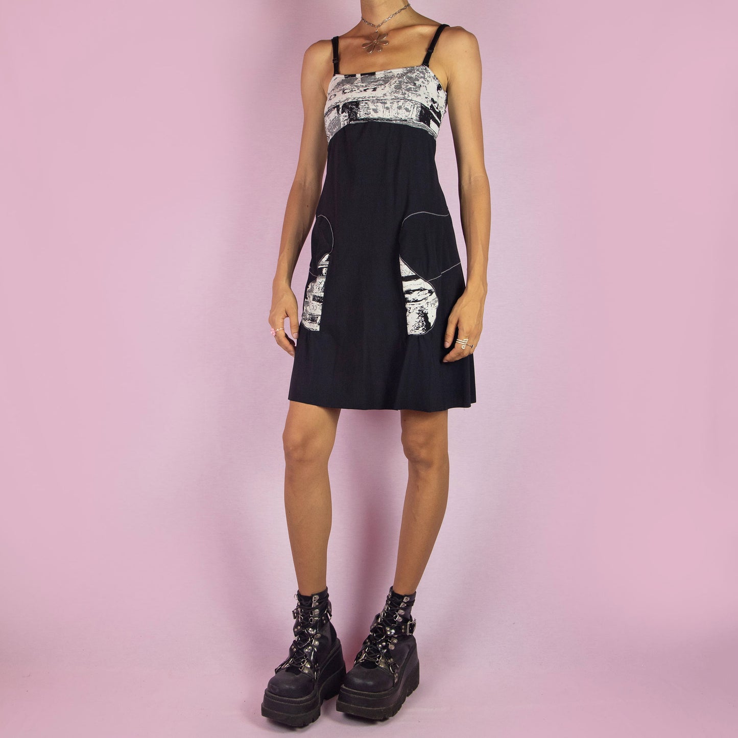 The Y2K Black Square Neck Dress is a vintage 2000s mini dress featuring a square neckline, adjustable straps, stretchy fabric, and a contrasting abstract print at the bust. With its A-line silhouette and casual style, it’s perfect for summer outings.