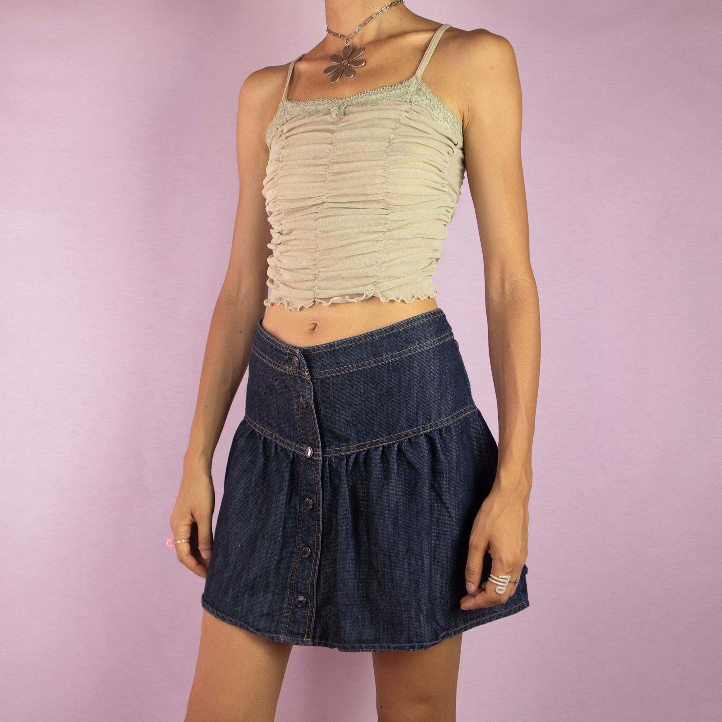 The Y2K Denim Flare Mini Skirt is a vintage 2000s piece featuring a mid-rise fit and a flared A-line silhouette. Made from dark-wash denim, this skirt showcases a tiered design with button-up detailing along the front. Ideal for casual wear and summer outings.