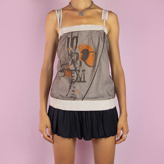 The Y2K Graphic Print Mesh Cami Top is a vintage 2000s piece featuring a unique graphic print on a semi-sheer mesh fabric. This deconstructed design includes asymmetric straps and button-down detailing at the back. Perfect for an avant-garde outfit. Made in France.