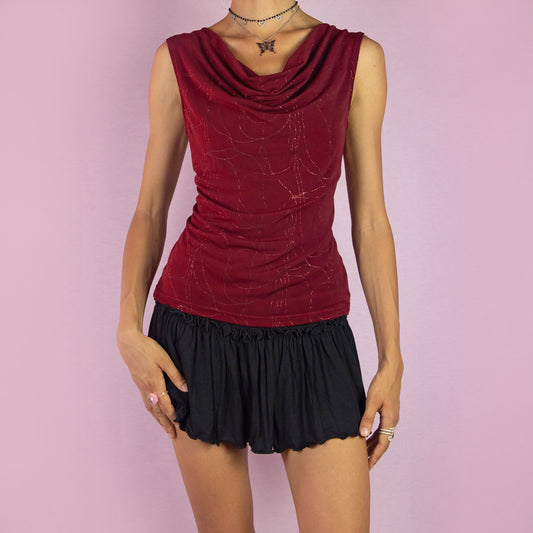 The Y2K Maroon Cowl Neck Sleeveless Top is a vintage 2000s burgundy red top featuring a draped cowl neckline, sleeveless design, and subtle glitter details throughout. Perfect for both casual and evening outfits. Made in France.